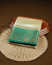 Light gold tussar saree featuring Elegant plain body, complemented by contrast green colour with Gold zari Floral kodi with Peacock Pattern border, comes with matching blouse piece.