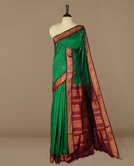 Green colour kalyani cotton saree featuring gold zari motifs on body, complemented by Maroon colour with Antique zari border, paired with matching blouse piece.