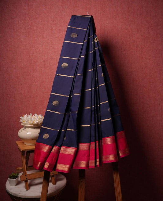 Navy blue colour semi silk saree highlighting gold zari strip pattern with motifs across body, featuring contrast rani pink colour border with gold zari pattern, comes with matching blouse .