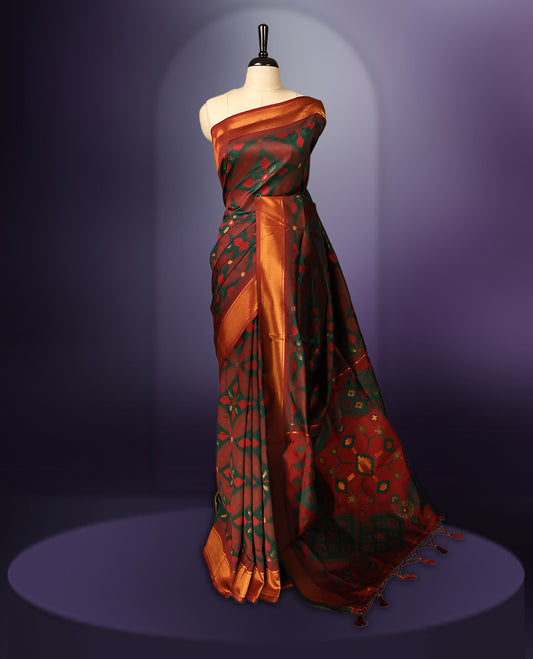 Maroon and green Ikat silk saree featuring intricate woven geometric and floral motifs across the body and pallu, complemented with a golden brown zari border and tassels, paired with a matching blouse piece.
