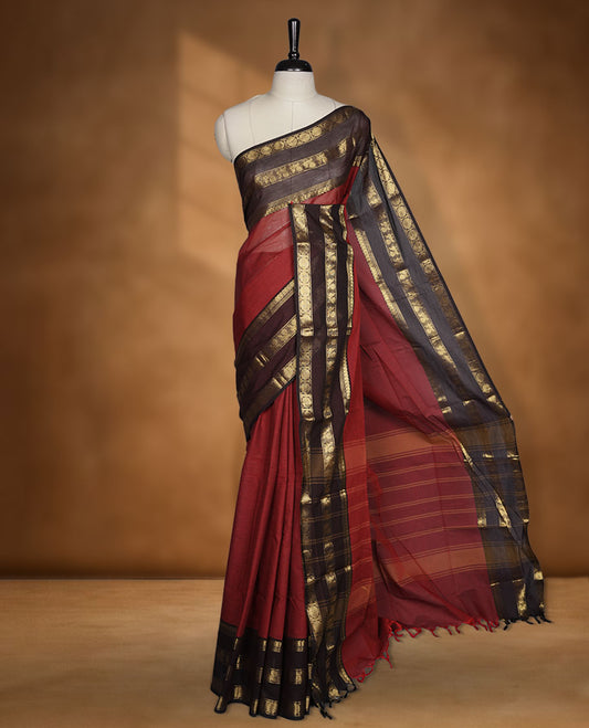 Red colour chettinad cotton saree featuring plain body, contrast chocolate brown colour with traditional gold zari border paired with matching blouse.