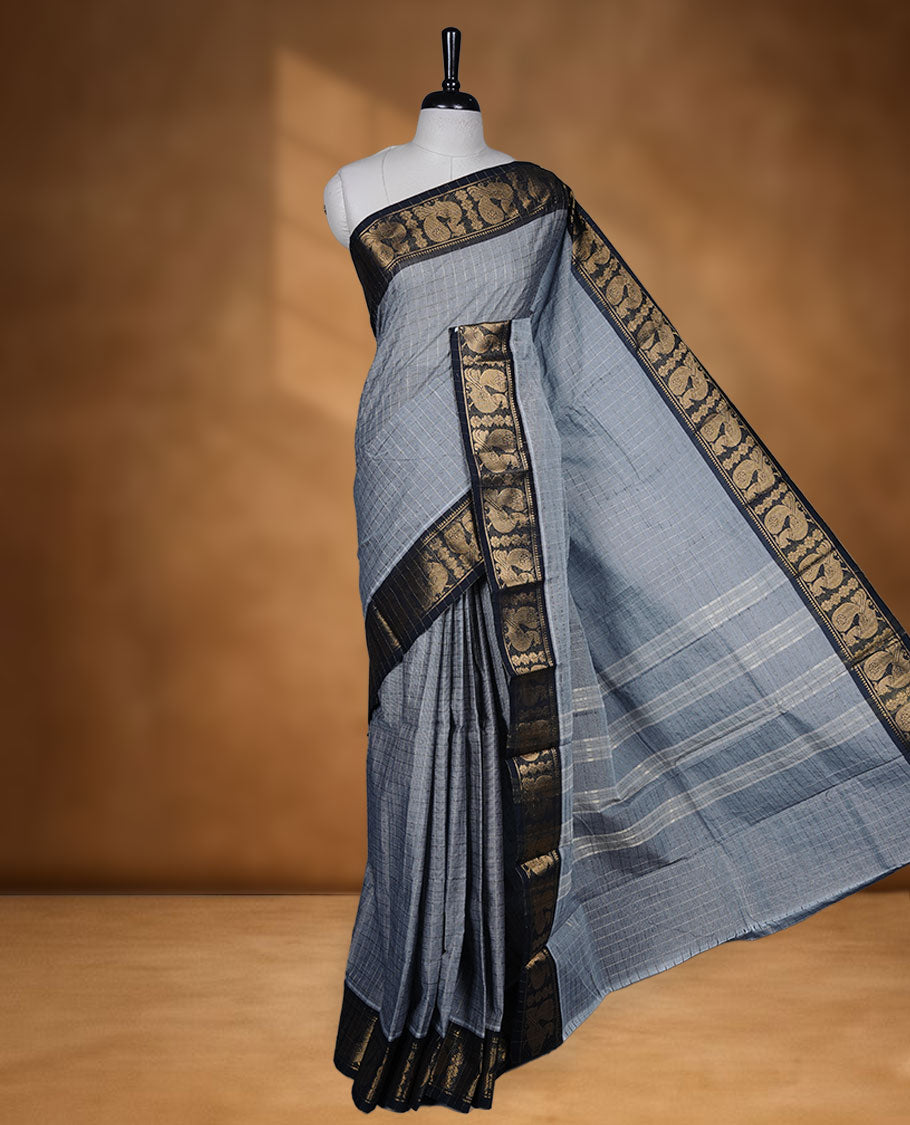 Grey colour sungudi cotton saree featuring gold zari check pattern across body, contrast Black colour with gold zari peacock and floral pattern on border, without blouse piece.