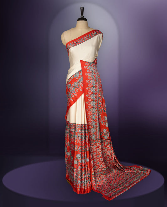 Cream colour saree enhanced with a vibrant red border and pallu, adorned with intricate blue and grey traditional motifs, comes with a matching blouse.