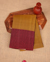 Fenugreek colour soft silk saree feaaturing self colour pattern on body, complemented by contrast maroon self colour pattern border, paired with matching blouse piece.