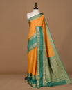 Mustard colour semi georgette saree featuring gold zari check pattern on body, complemented by contrast green colour with zari border, paired with matching blouse piece.