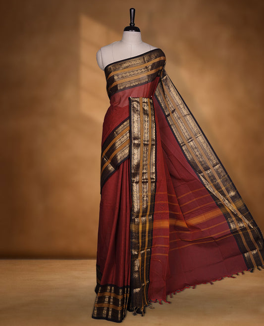 Maroon colour chettinad cotton saree featuring plain body, contrast chocolate brown and mustard colour with traditional gold zari border paired with matching blouse.