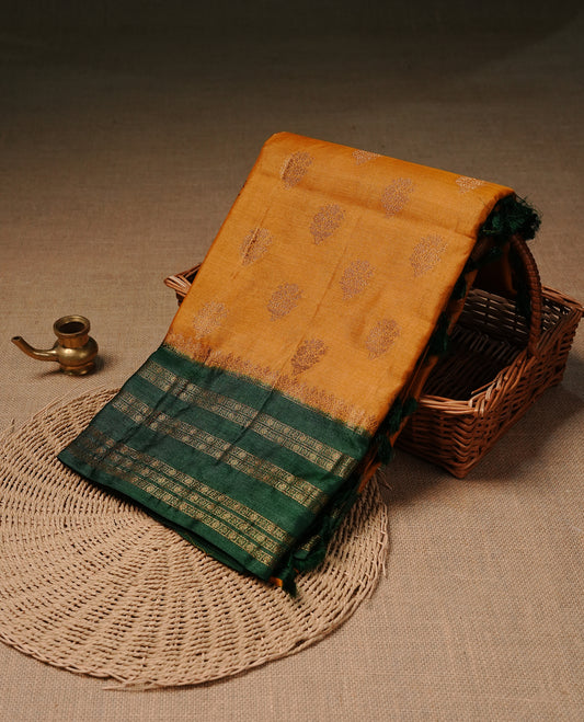 Mustard colour pure tussar banaras silk saree featuring gold zari motifs on body, highlighting contrast green colour with zari border, paired with matching blouse piece.