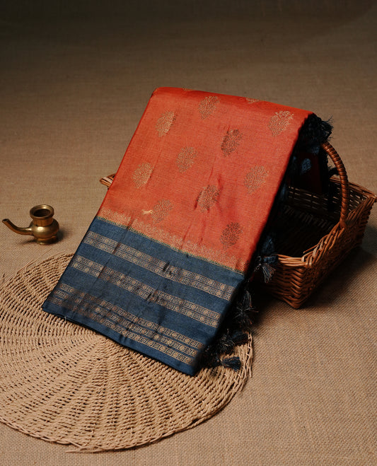 Rust orange colour pure tussar Banaras silk saree featuring elegant gold zari motifs across the body, complemented by a contrast teal border with rich zari detailing. Comes with a matching blouse piece