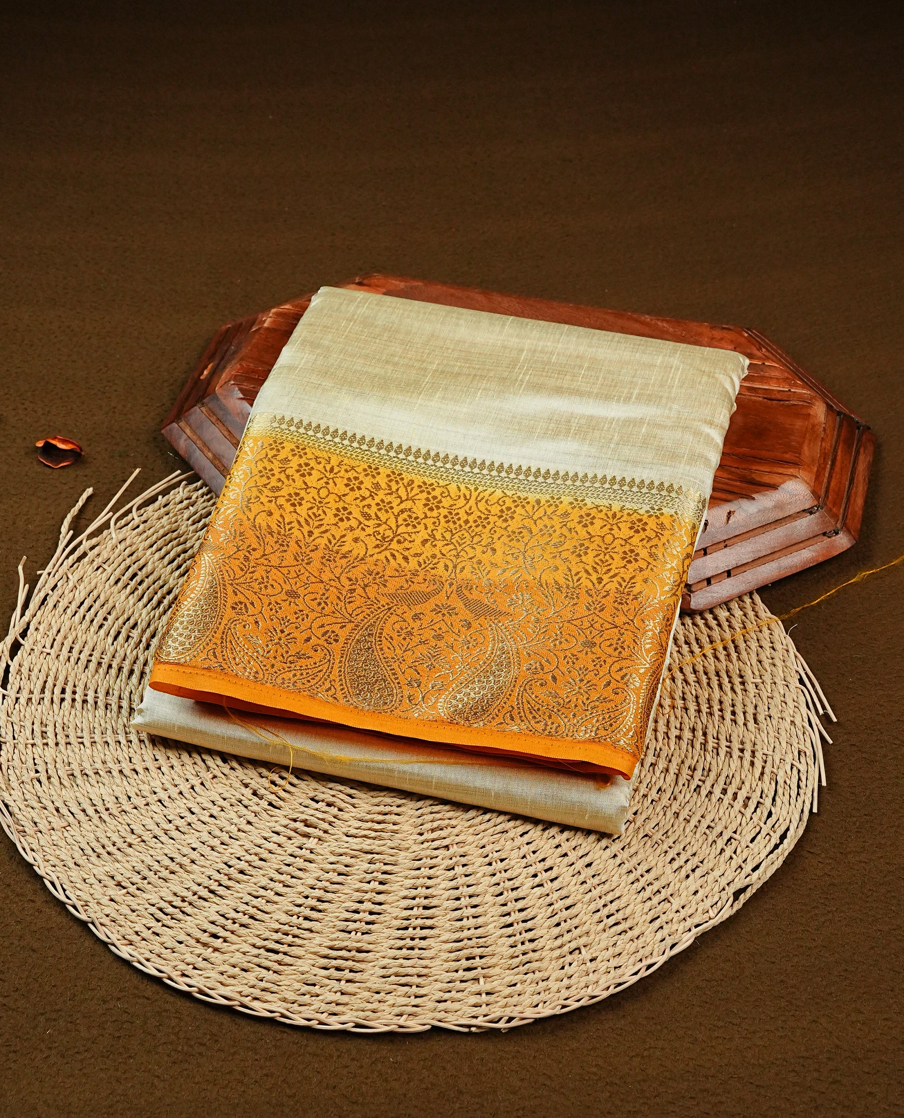 Light gold tussar saree featuring Elegant plain body, complemented by contrast Orange yellow  colour with Gold zari Floral kodi with Peacock Pattern border, comes with matching blouse piece.