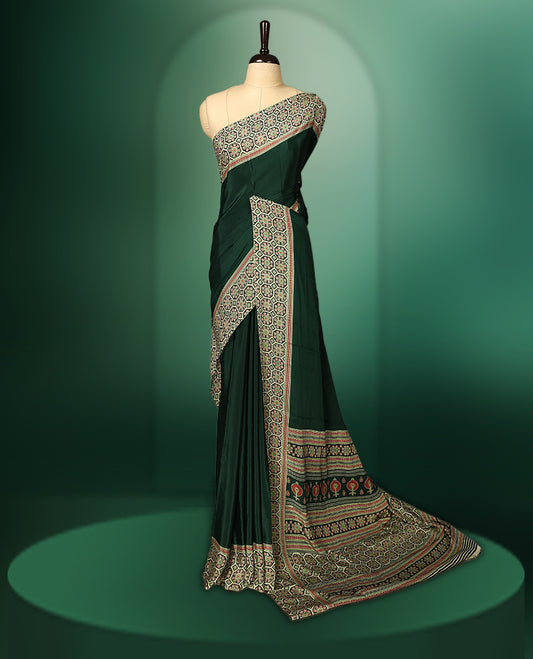 Bottle green colour saree beautifully detailed with intricate multicolour woven borders and an elaborate patterned pallu, paired with a matching blouse.