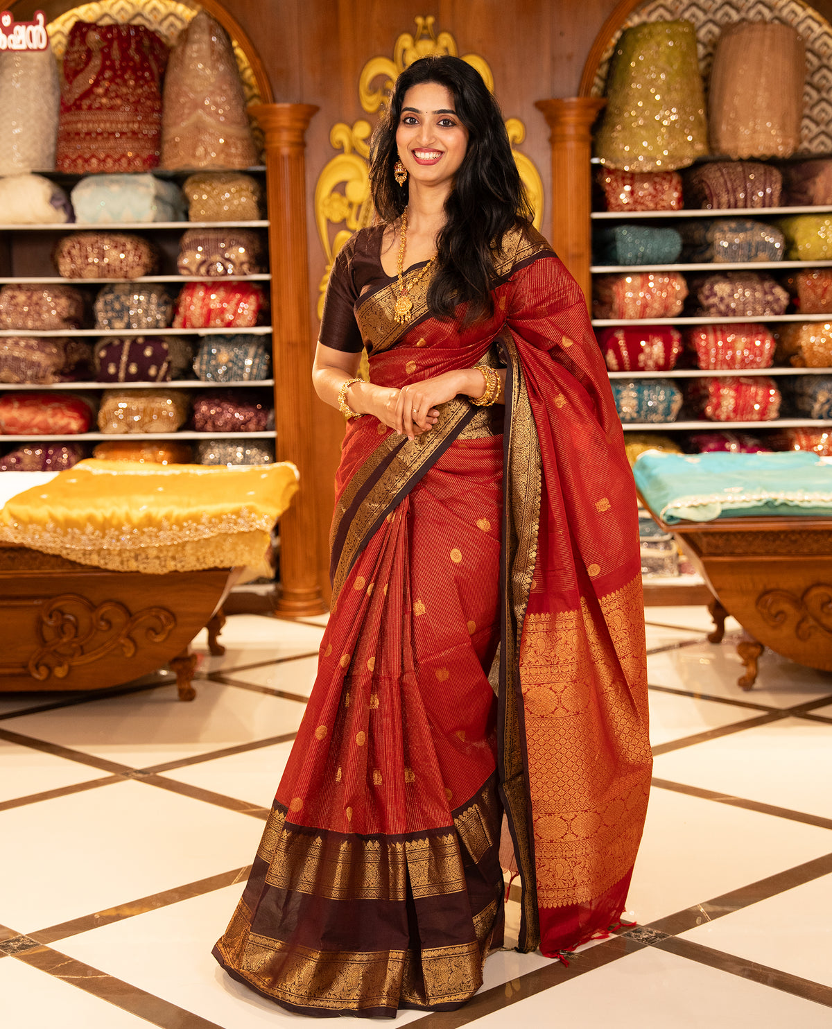 Maroon with Brown Chettinad cotton saree featuring Gold zari strips with peacock motifs on body, complemented by contrast colour border with zari design & grand pallu, comes with matching blouse piece.