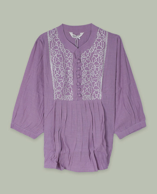 Lilac three-quarter sleeve tunic top with rounded band neckline, white floral embroidered yoke, fabric-covered button placket, and soft pleating below the yoke.