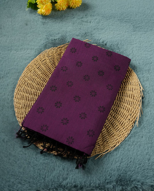 Grape Purple colour poly cotton saree with black floral butti motifs on the body, paired with a matching pallu featuring black ornate floral jaal and stripes on the border, and a coordinated all‑over black paisley printed blouse piece.