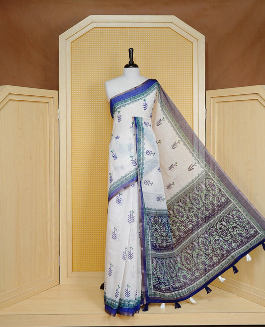 Off White colour Semi Linen Saree Featuring Elegant Floral Print on body, Contrast Blue Colour Border, Minimal Floral print Pallu, Unique Tassel Detailing For Festive Vibe, Contrast Colour Blouse piece.