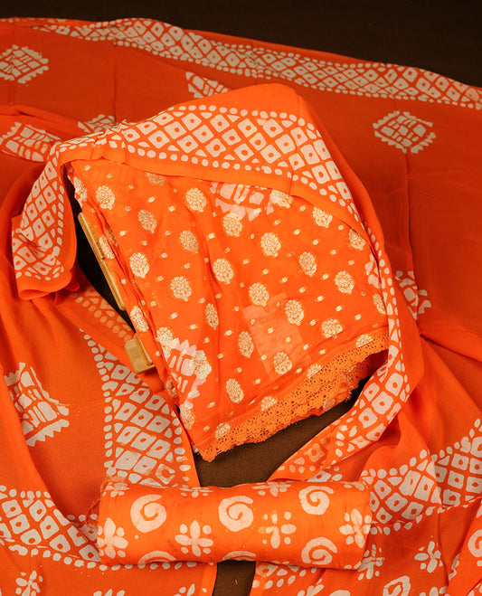 Bright orange colour churidar material featuring elegant gold butta work on the front panel, paired with a printed dupatta and matching bottom.