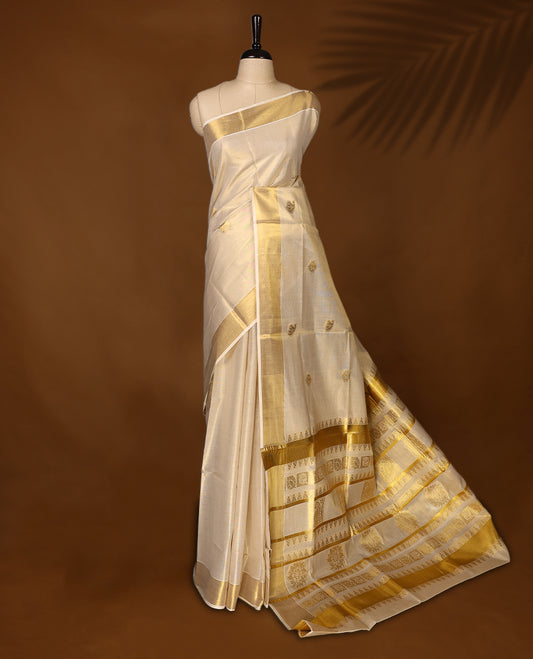 Classic Kerala Kasavu saree with golden motifs and a grand woven pallu, The ivory tone with intricate zari detailing makes it ideal for weddings and festivals, Pair with gold jewelry for a graceful, regal look.