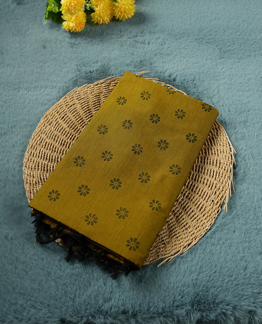 Dark Mustard colour poly cotton saree with black floral butti motifs on the body, paired with a matching pallu featuring black ornate floral jaal and stripes on the border, and a coordinated all‑over black paisley printed blouse piece.