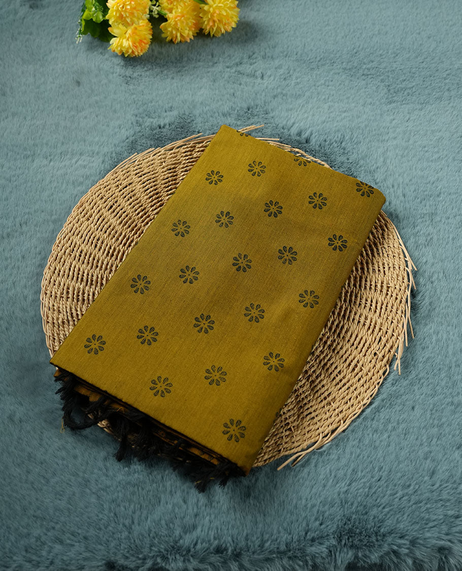 Dark Mustard colour poly cotton saree with black floral butti motifs on the body, paired with a matching pallu featuring black ornate floral jaal and stripes on the border, and a coordinated all‑over black paisley printed blouse piece.