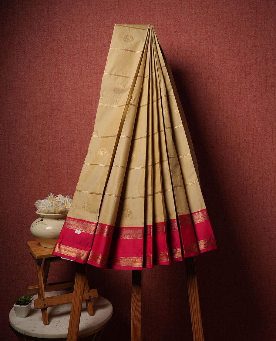 Cream colour semi silk saree highlighting gold zari strip pattern  and motifs across body, featuring contrast pink colour border with gold zari pattern, comes with matching blouse .