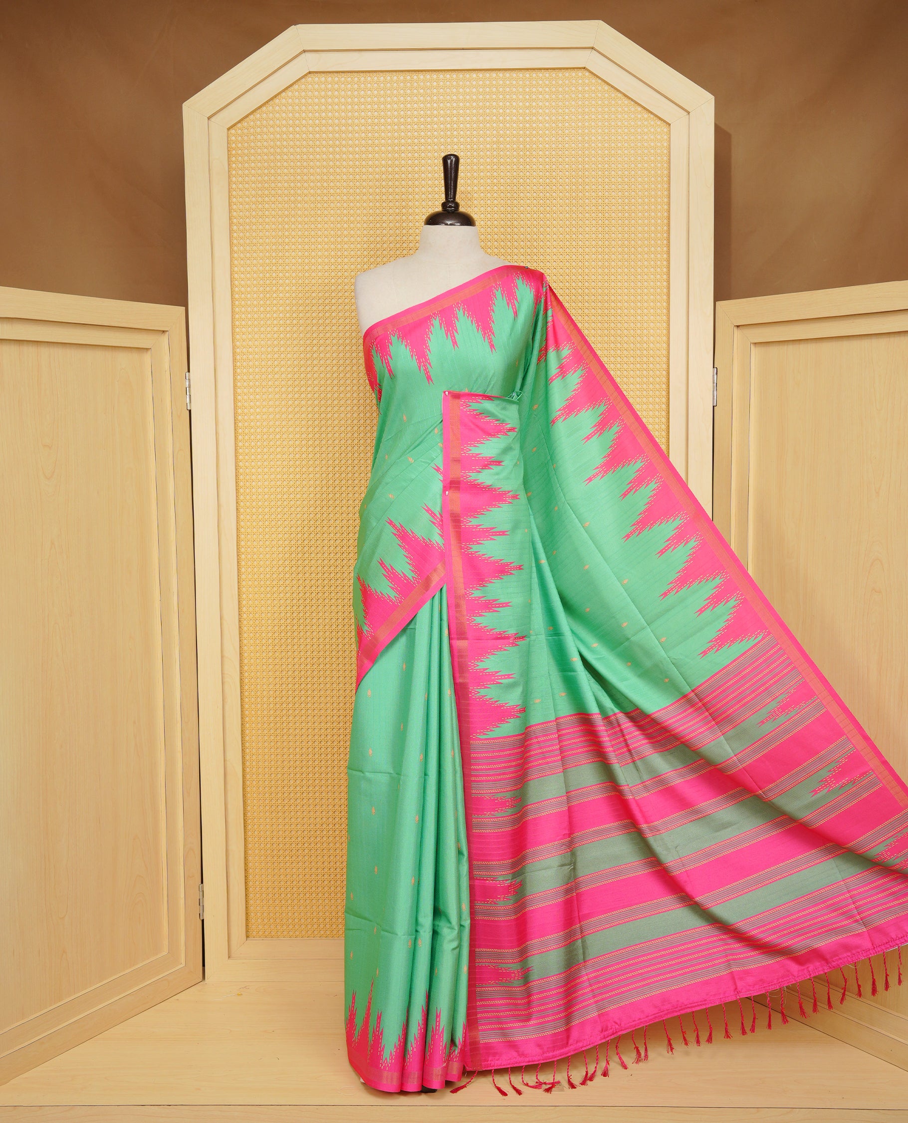 Leaf Green and Rani pink Colour Kattan silk saree featuring buttas all over the body, a temple-designed border &  a contrasting striped pallu with tassels. Paired with a matching contrast-striped blouse piece.