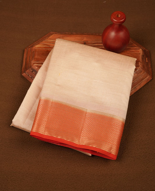Cream colour tussar silk saree featuring elegant plain body, contrast orange colour border with gold zari, comes with matching blouse piece.