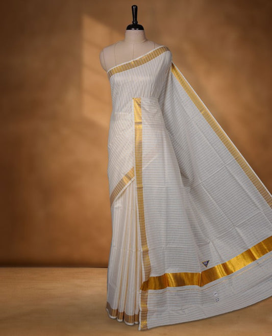 Off-white colour cotton Kerala saree featuring fine golden stripe detailing across the body, highlighted by a rich gold kasavu border along the edges and pallu, and paired with a matching striped blouse.