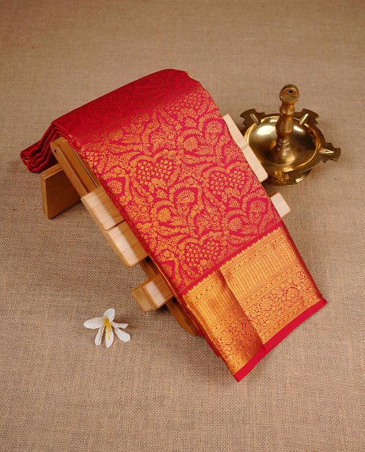 Deep red colour kancheepuram silk saree featuring gold zari pattern across body, complemented by selfcolour border traditional zari border, paired with matching blouse piece.