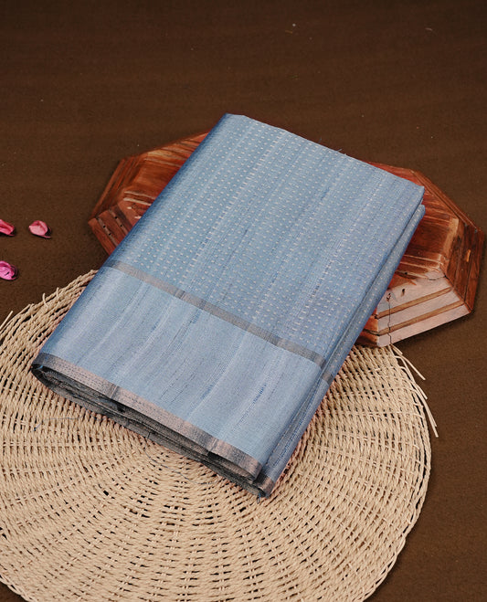Steel blue colour semi tussar silk saree featuring elegant gold zari dotted stripes across the body, enhanced with a rich zari woven border. Comes with a matching blouse piece.