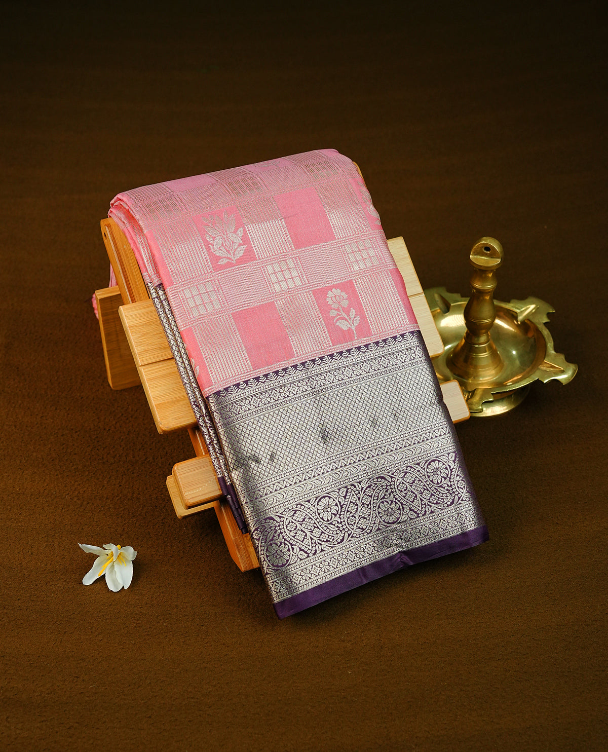 Baby pink colour semi wedding saree featuring light gold zari box with flower motifs across the body, complemented by contrast purple traditional border. Comes with a matching blouse piece.