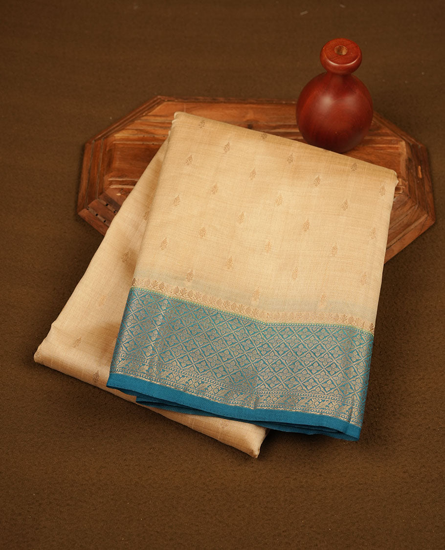 Light gold colour semi tussar saree featuring gold zari buttas across body, contrast teal colour gold zari border and comes with matching blouse piece.