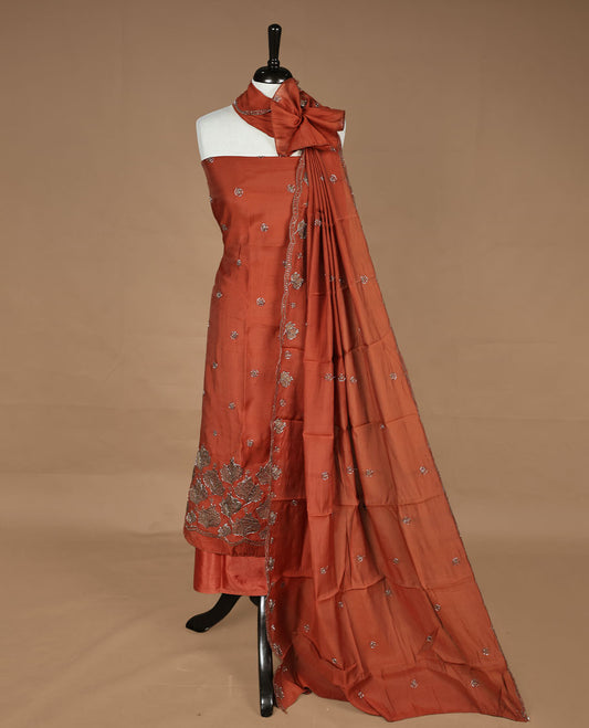 Brick orange colour churidar materal featuring floral cut beats and thread work on body, paired with matching bottom and dupatta.
