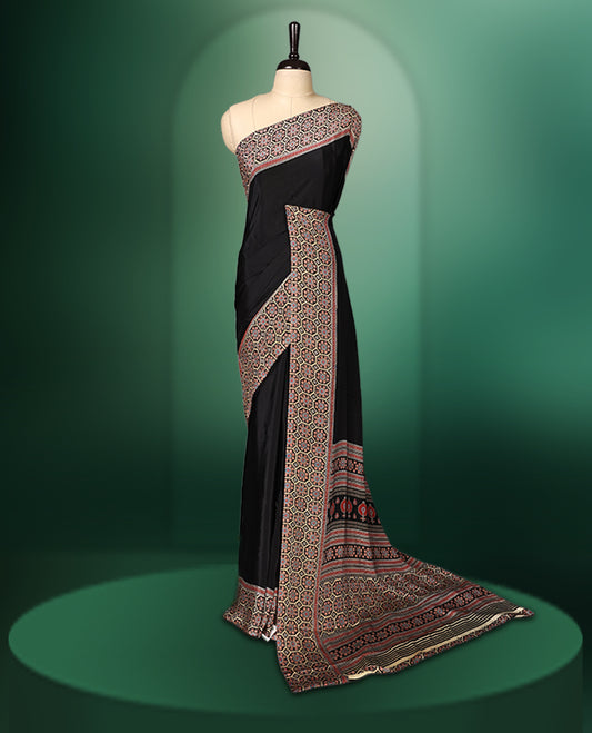 Black colour semi modal saree featuring an intricately woven multicolour ethnic patterned border and pallu, highlighted with traditional motifs, and paired with a matching blouse