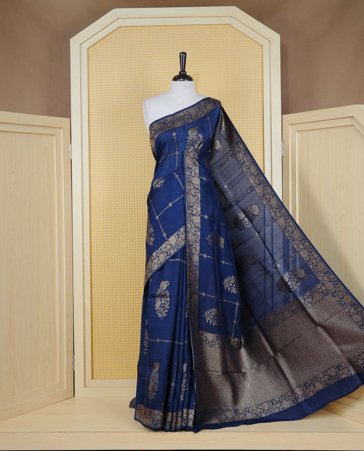 Navy blue colour semi banaras tussar georgette saree featuring gold zari floral pattern body, finished with gold zari floral motifs on border and paired with matching blouse piece.