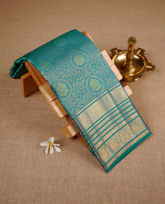 Peacock colour kancheepuram silk saree featuring gold zari pattern across body, complemented by selfcolour border traditional zari border, paired with matching blouse piece.