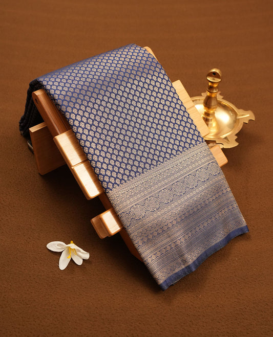 Blue colour semi silk brocade saree featuring intricate Gold patterns across the body, complemented by a Self colour woven border and pallu, paired with a matching blouse.