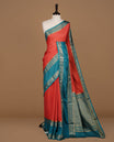 Red colour semi georgette saree featuring gold zari check pattern on body, complemented by contrast teal colour with zari border, paired with matching blouse piece.