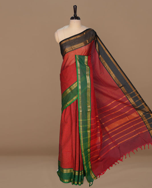 Maroon colour chettinad cotton featuring gold zari check pattern on body , complemented by contrast Green colour with gold zari border, paired with matching blouse piece.