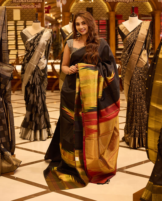Black colour pure silk saree featuring a plain body, highlighted with a rich multicolour ikat-inspired zari pallu in gold, green and deep red hues, complemented by a tissue temple border and beautifully paired with a matching blouse.