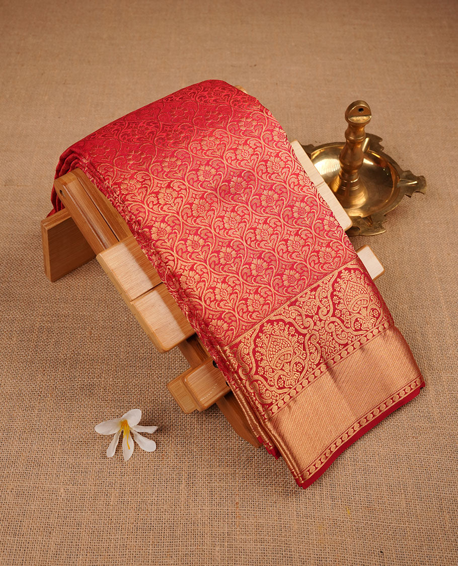 Cherry red colour kancheepuram silk saree featuring floral zari jacquard on body with traditional zari border, paired with matching blouse piece.