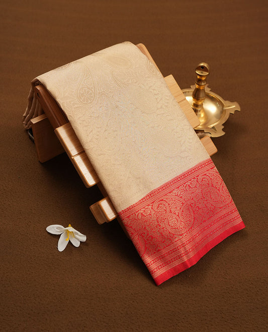 Cream colour semi silk brocade saree featuring intricate light Gold Floral kodi and leaf patterns across the body, complemented by a contrast red colour woven border and pallu, paired with a matching blouse.