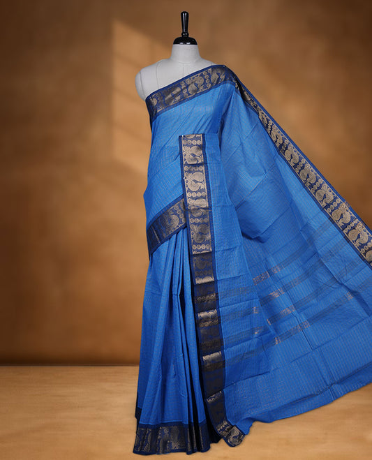 Blue colour sungudi cotton saree featuring gold zari check pattern across body, contrast Dark blue colour with gold zari peacock and floral pattern on border, without blouse piece.