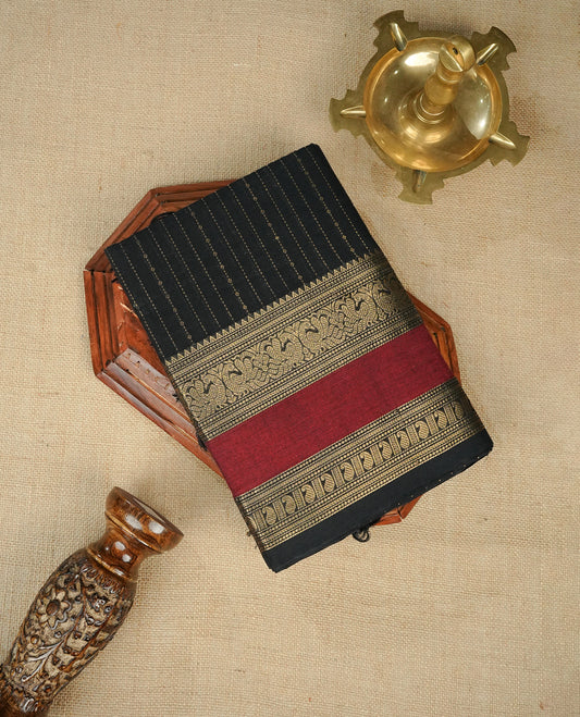Black colour chettinad cotton saree Featuring Gold zari Strips on body, complemented by contrast Maroon colour with zari border, comes with matching blouse piece.