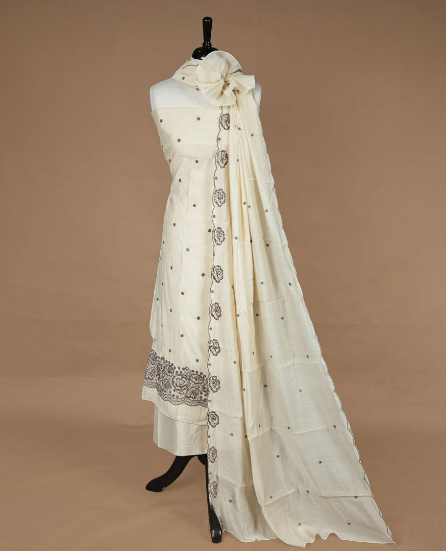 Off white colour churidar material featuring floral cut beats and thread work on body, paired with matching bottom and dupatta.