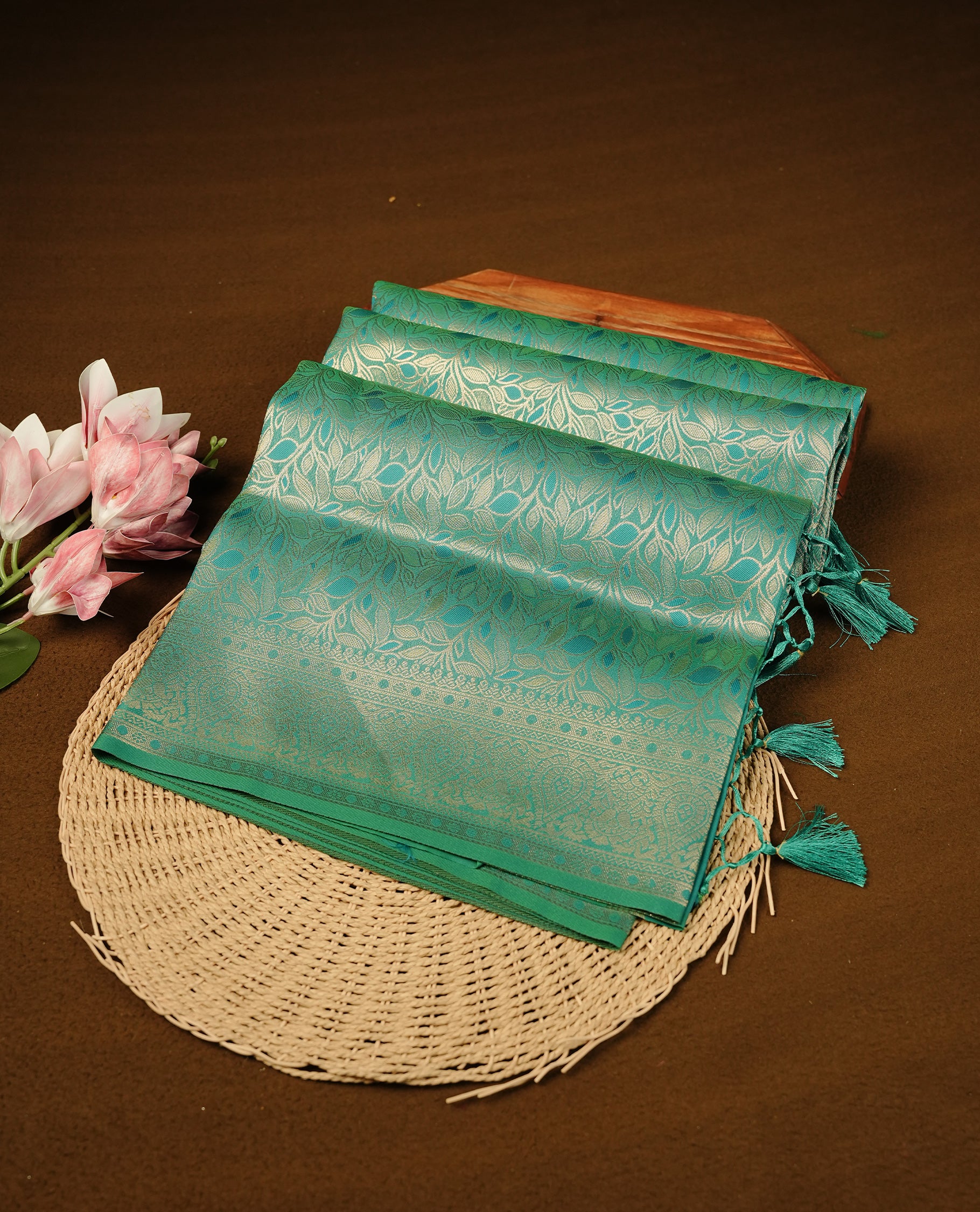 Sea Green Colour Softie Silk Saree Featuring An All Over Gold Woven Leaf Pattern, Finished With A Matching Border Adorned With Intricate Paisley And Floral Motifs, Paired With A Matching Blouse Piece.