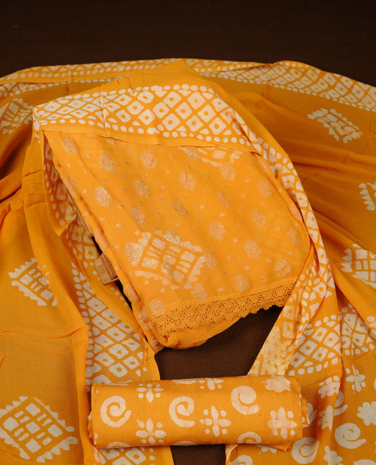 Yellow orange colour churidar material featuring elegant gold butta work on the front panel, paired with a printed dupatta and matching bottom.