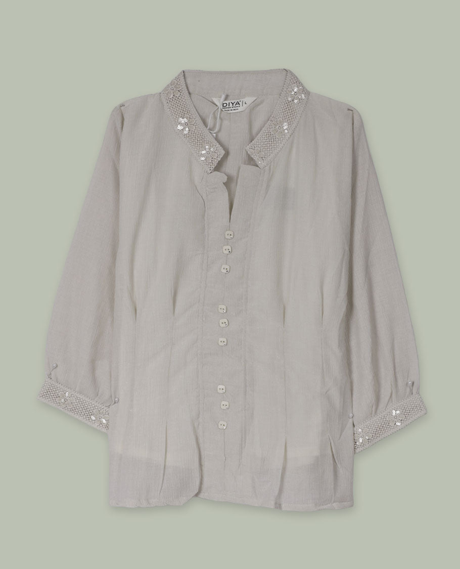 Cream three-quarter sleeve shirt top with embellished band collar and cuffs, front button placket, and soft pleating below the placket.