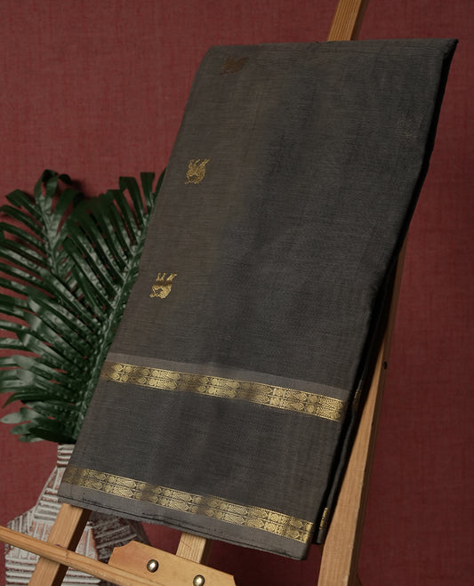 Grey colour Pure Kanchi cotton saree adorned with subtle golden buttas all over, highlighted by a rich zari woven border with traditional motifs  & Includes a matching blouse piece for a complete look.
