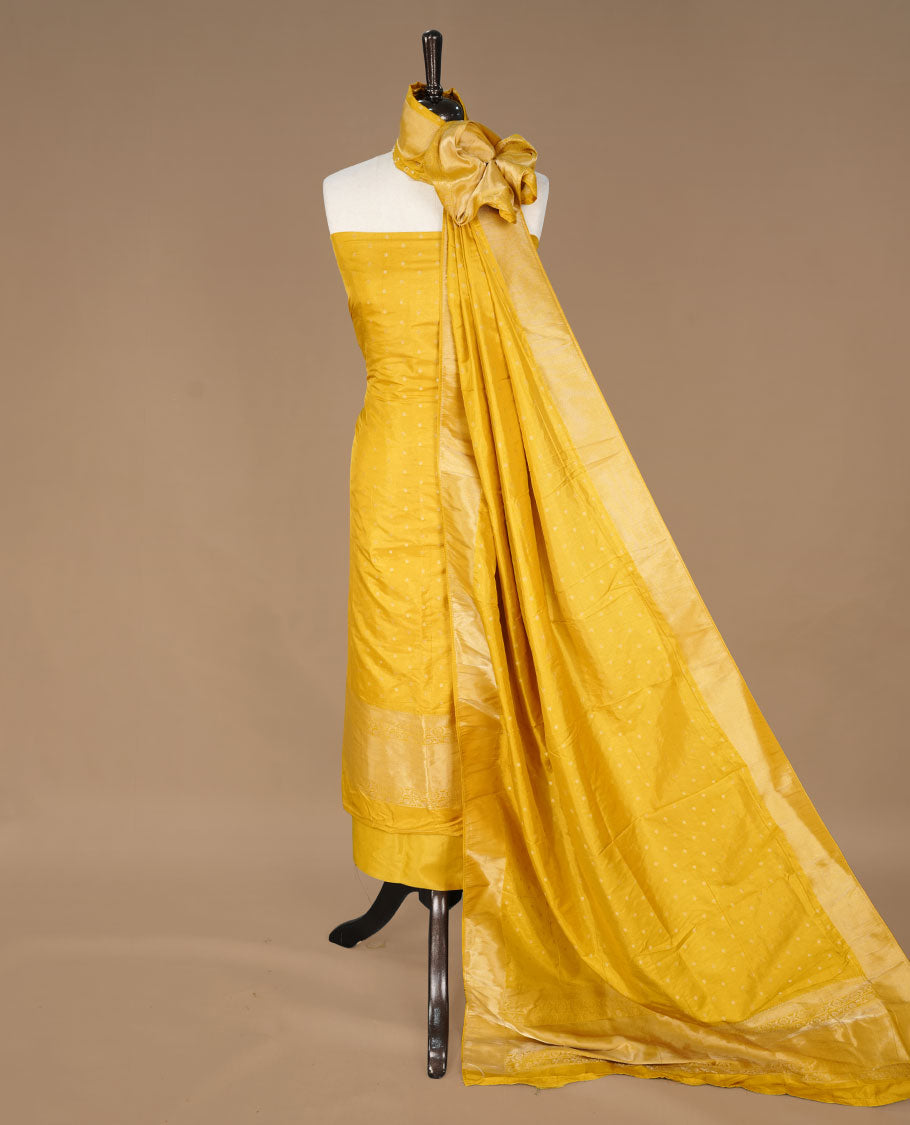 Yellow colour churidar material featuring Gold zari buttas on body, paired with matching bottom and dupatta.