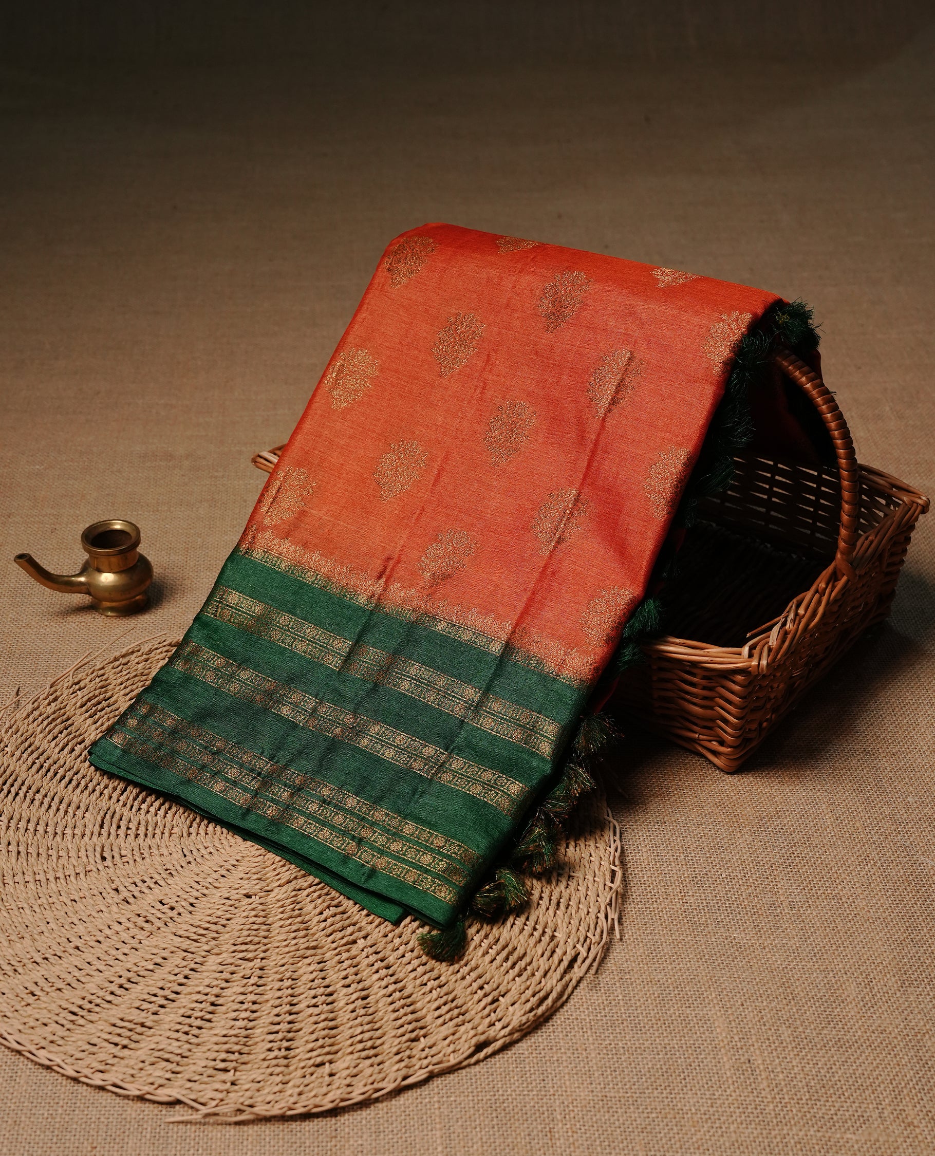 Rust orange colour pure tussar Banaras silk saree featuring elegant gold zari motifs across the body, complemented by a contrast Green border with rich zari detailing. Comes with a matching blouse piece