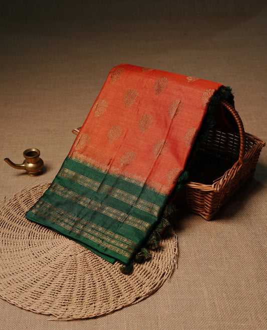 Rust orange colour pure tussar Banaras silk saree featuring elegant gold zari motifs across the body, complemented by a contrast Green border with rich zari detailing. Comes with a matching blouse piece